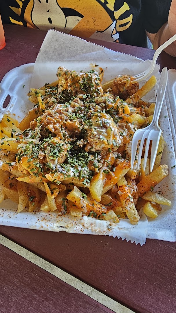 Loaded lobster fries topped with seasoning, cream sauce, and fresh herbs in a paper tray